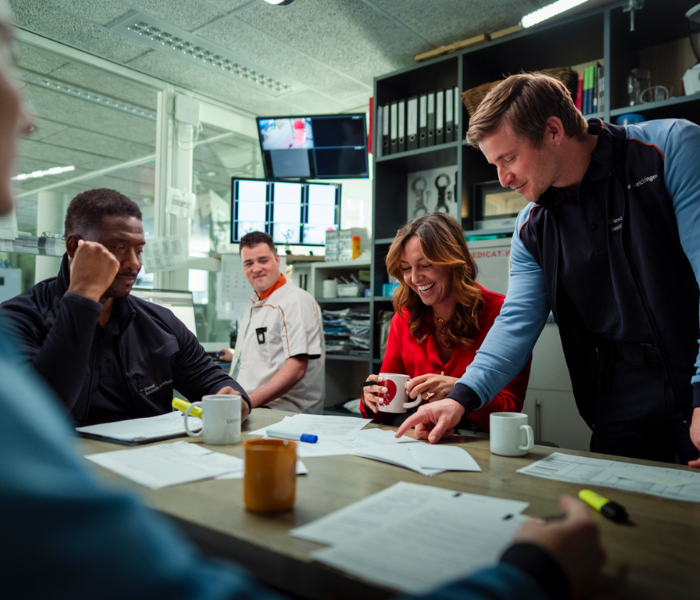 Vergadering met documenten en koffiemokken.