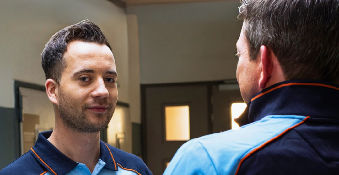 Twee collega’s praten in een gangruimte