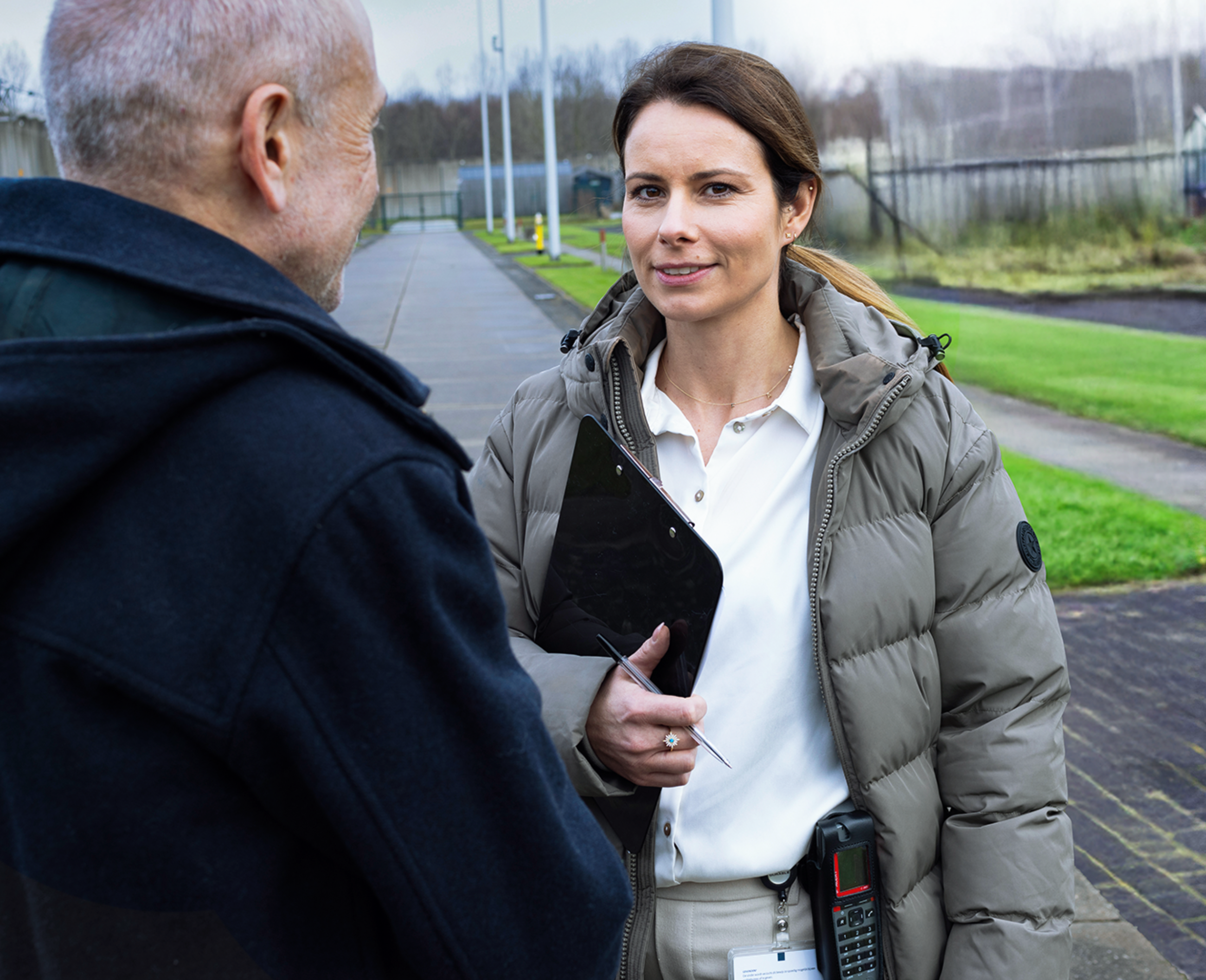Vrouw spreekt man buiten en noteert gegevens.