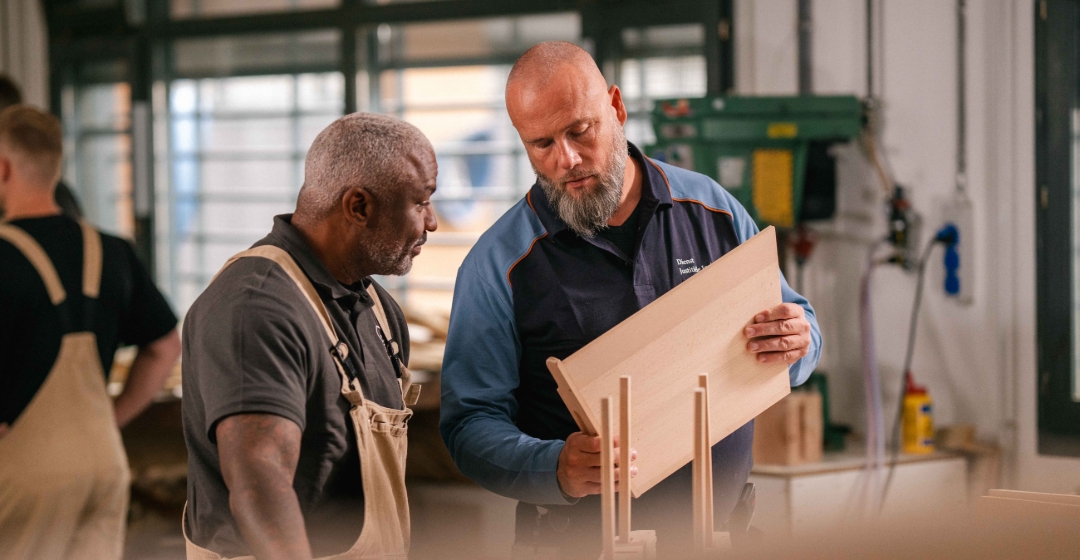 Twee vakmensen bekijken een houten paneel in werkplaats