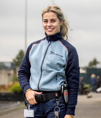 Lachende vrouw in uniform staat buiten op terrein