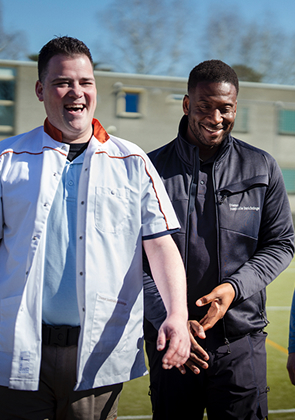 Begeleiders lopen met persoon op sportveld