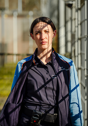 Vrouwelijke justitiemedewerker bij hek in zonlicht