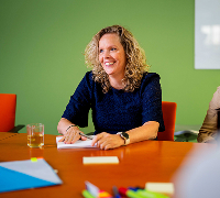 Persoon schrijft aan een vergadertafel