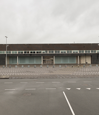 Groot gevangenisgebouw met hek en lege parkeerplaats