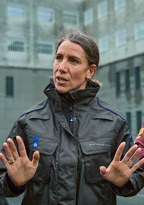 Vrouw in uniform spreekt rustig met handen omhoog.