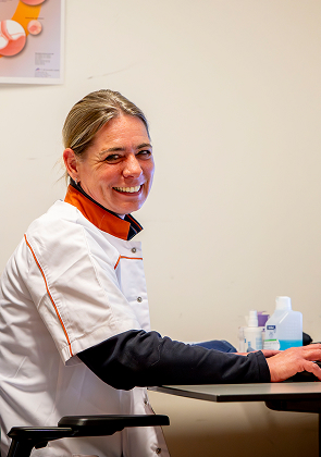 Zorgmedewerker lacht aan tafel met middelen in kamer