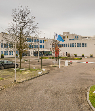 Ingang van groot kantoorgebouw met parkeerplaats