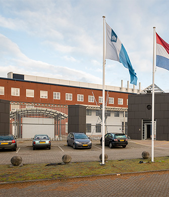 Vooraanzicht van groot gebouw met vlaggen en parking