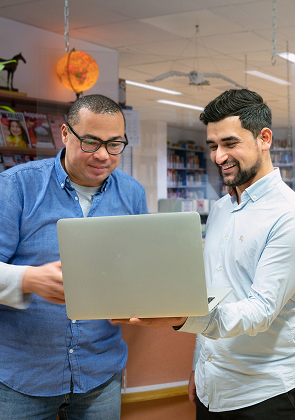 Twee collega’s bekijken samen laptop in bibliotheek