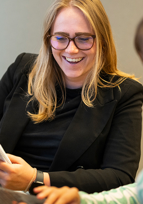 Twee collega’s lachen en werken samen aan laptop