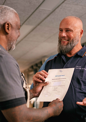Medewerker overhandigt certificaat en praat vriendelijk