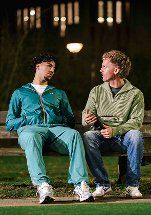 Twee mannen praten samen op bankje in de avond