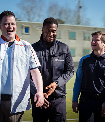 Medewerkers begeleiden persoon over buitenterrein