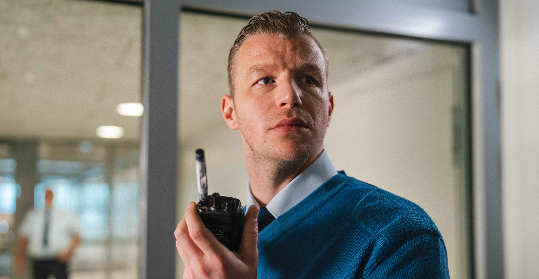 Medewerker met portofoon in toezichtruimte