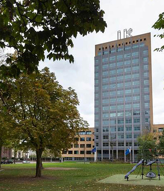 Hoog kantoorgebouw naast park met bomen
