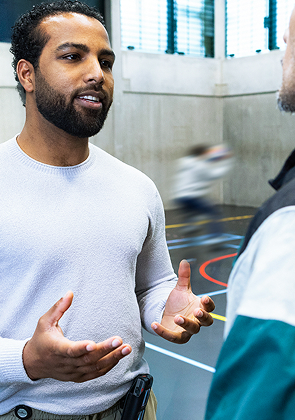 Man praat met collega in sporthal