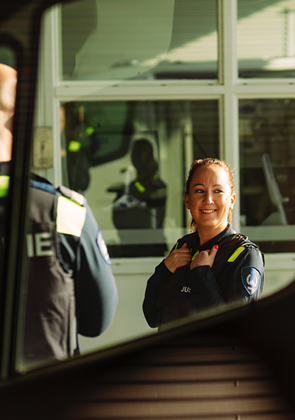 Justitiemedewerkster lacht bij dienstvoertuig