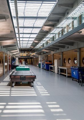 Lichte gevangenisgang met cellen en gemeenschappelijke ruimte