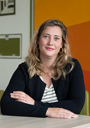 Vrouw zit aan tafel en kijkt in camera