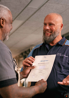 Medewerker reikt certificaat aan en glimlacht vriendelijk