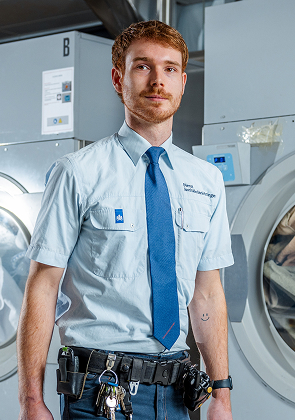 Medewerker in uniform bij industriële wasmachines