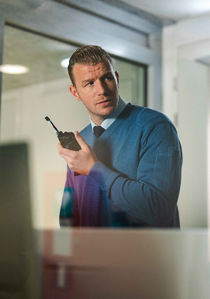 Man met portofoon in modern kantoor kijkt alert opzij