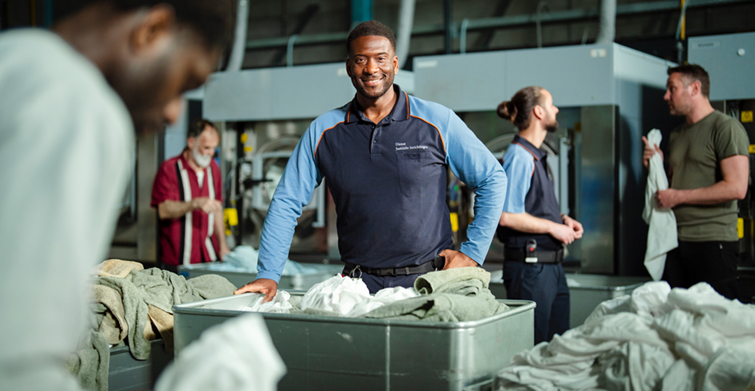 Medewerkers werken samen in een industriële wasserij met waskarren