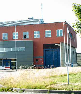 Modern bakstenen bedrijfsgebouw met blauwe poort en groen
