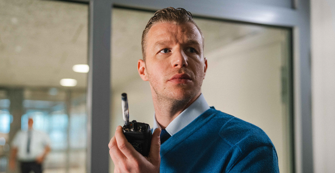 Medewerker met portofoon kijkt alert om zich heen