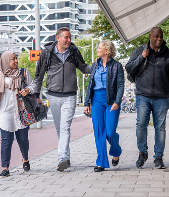 Drie mensen lopen pratend langs een gebouw samen!!
