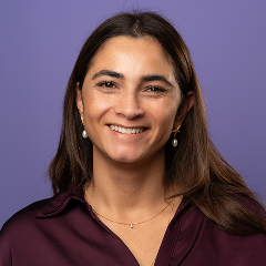 Portret van glimlachende vrouw met donker haar op paarse achtergrond