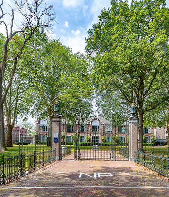 Ingang van gebouw met hek en bomen