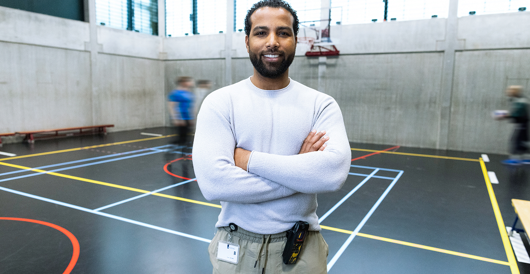 Begeleider staat in sportzaal met spelende mensen
