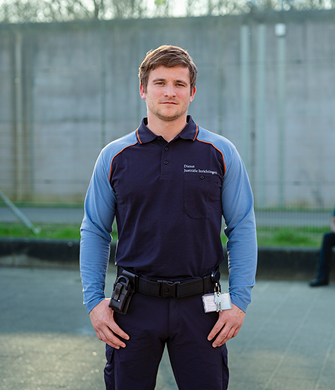 Jonge beveiliger van Dienst Justitiële Inrichtingen voor hoge muur