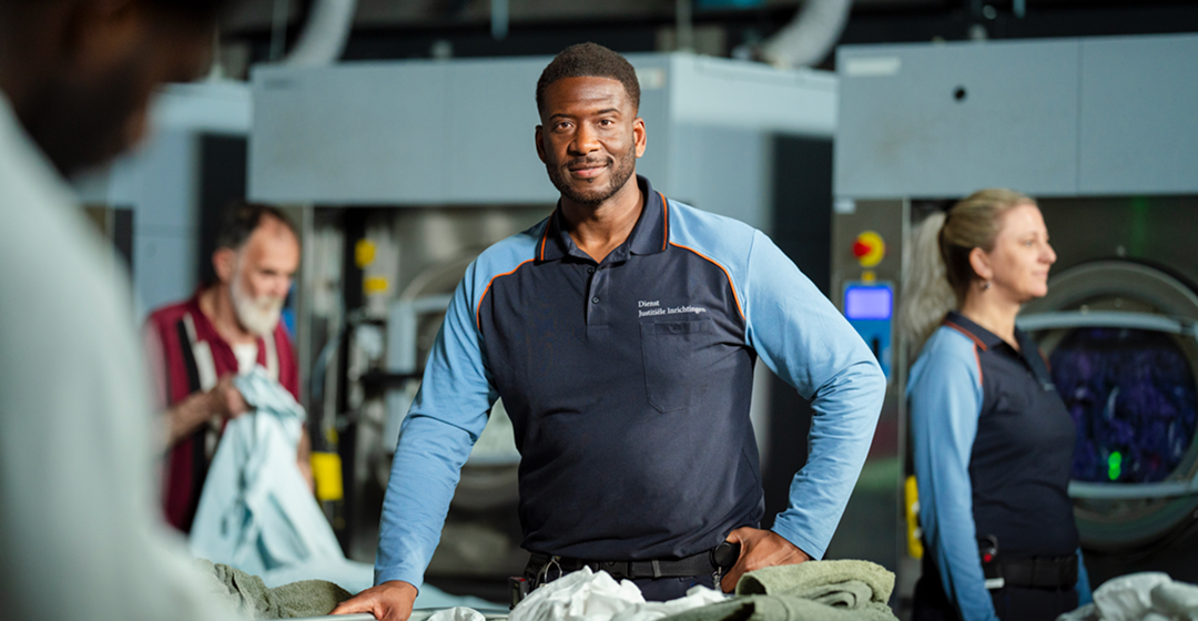 Bewaker in wasserij met was, collega’s werken mee