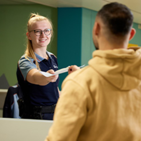 Medewerker overhandigt document aan bezoeker