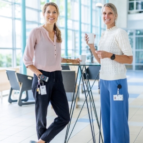 twee collega’s met koffie bij statafel in hal