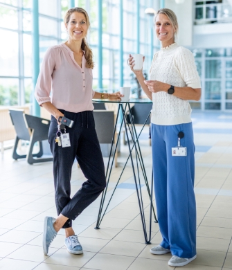 twee collega’s met koffie bij statafel in hal