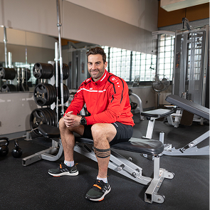 Persoon zit op fitnessbank in sportschool