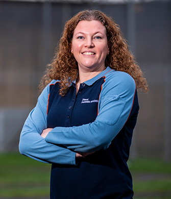 Vrouw in uniform staat glimlachend met armen gekruist