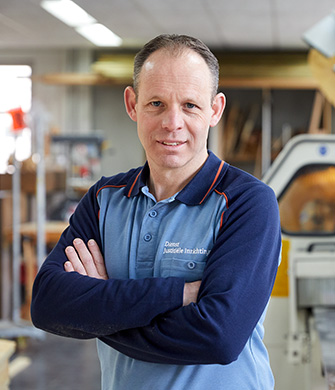 Medewerker in werkplaats met armen gekruist