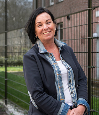 Vrouw lacht buiten bij hek en bakstenen gebouw nu