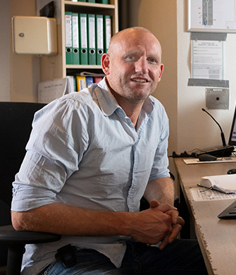 Man zit glimlachend aan bureau in kantoorruimte