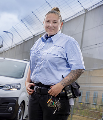 Medewerkster staat bij hek naast auto