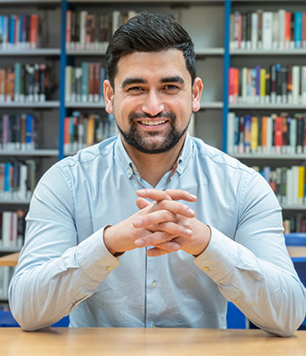 Persoon zit aan tafel in ruimte met boekenrekken