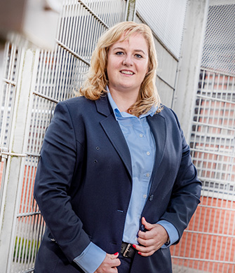 Persoon in uniform staat bij metalen hekwerk