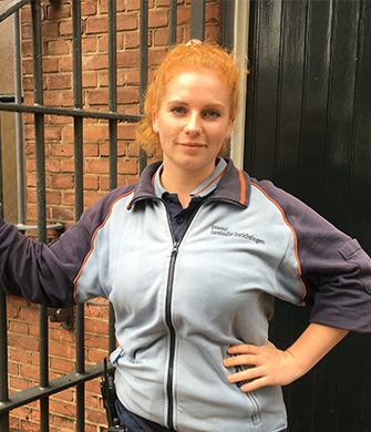 Vrouw in uniform staat bij hek en deur