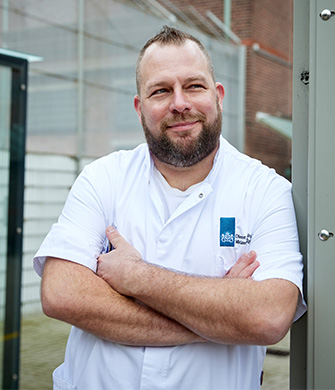 Persoon in witte jas met armen gekruist buiten