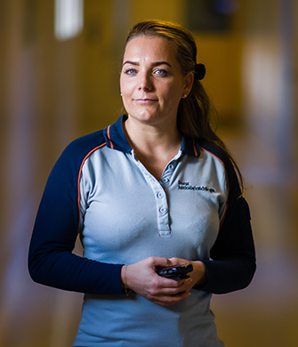 Medewerker loopt door gang met portofoon in hand
